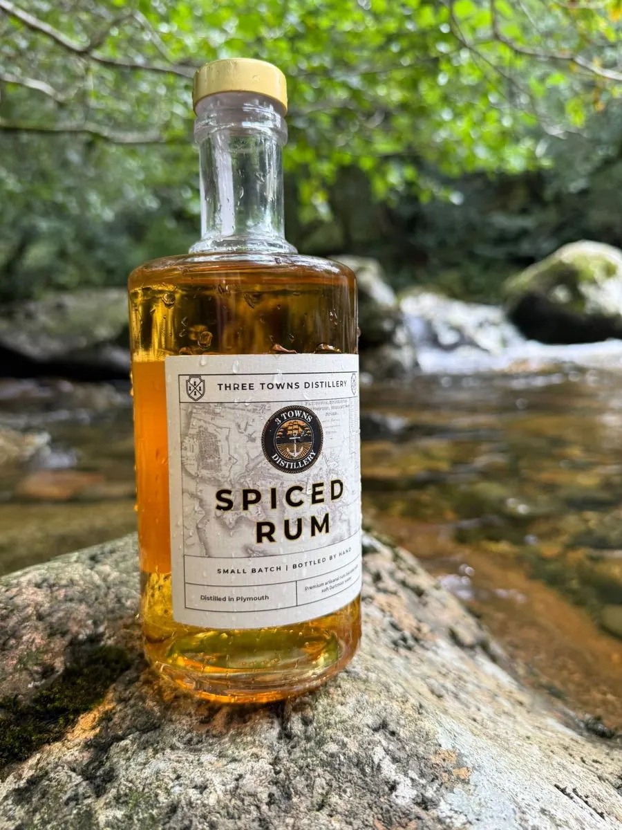 Three Towns Spiced Rum bottle beside a running Dartmoor stream